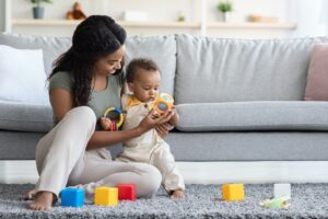 Activities With Babies. Black Mom Playing Toys With Infant Son At Home for best tips for parents of babies with cerebral palsy